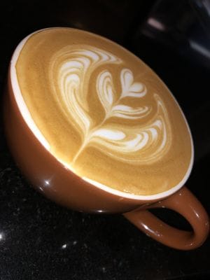 Latte with rosette art in terracotta cup